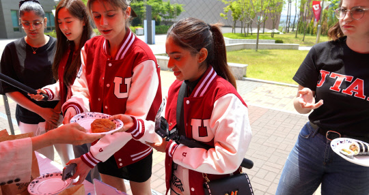 유타대 아시아캠퍼스 학생이 인도 유명 연예인 아누쉬카 센에게 꽈배기를 건네고 있다.(아시아랩 제공)